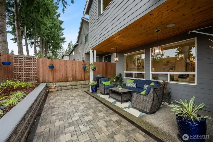 The backyard space is a tranquil oasis with a covered area, custom patio/rock wall and privacy fence.