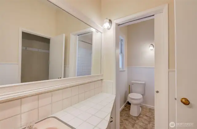 Main floor bathroom w/ pocket door separating toilet & tub from sink.