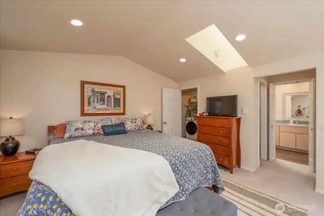Primary bedroom suite with vaulted ceilings & skylight.