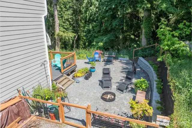 Expansive fenced in backyard with fire pit.