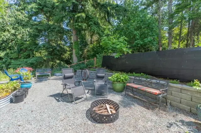 Expansive fenced in backyard with fire pit.