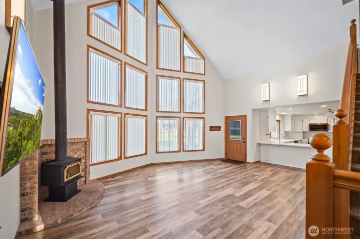 What a beautiful and dramatic room, with two stories of glass windows. Easy care LVP flooring and a cozy wood stove for chilly nights