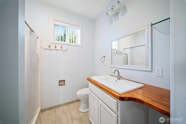 Main floor primary bath with charming wood counter and loads of light