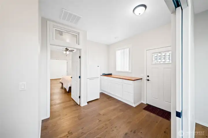 This flex space off of the main floor primary would make a great kitchen. The bar here is plumbed and the refrigerator can stay. The exterior door leads to the hangar and a wash station with hot and cold water