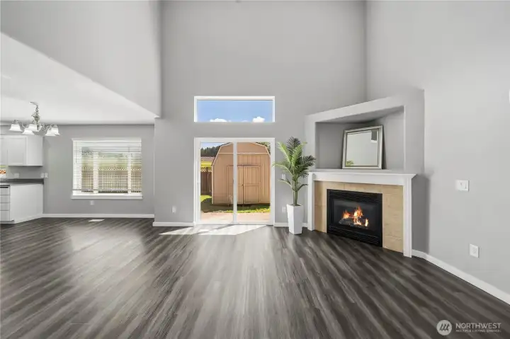 Open and airy living space with vaulted ceilings, large windows, and cozy fireplace