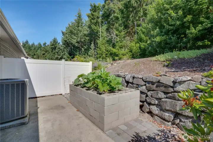 Tucked behind the garage, you'll find a private patio, a charming garden bed, and a peaceful canopy of mature trees—the perfect place to relax, garden, or simply enjoy the outdoors