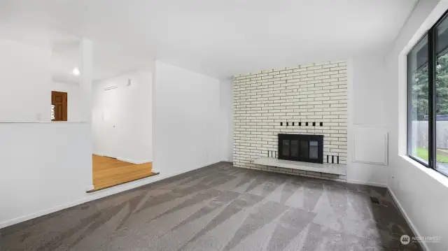 Formal living room steps down to this bright and rustic space featuring the first of 4 fireplaces and large window.