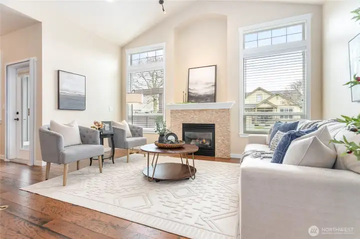 Abundant light welcomes you into this vaulted living room with extra tall windows, cozy gas fireplace & alcove