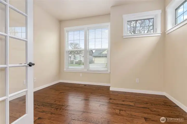 Love the extra casement windows and french doors in this large bedroom with hardwood flooring