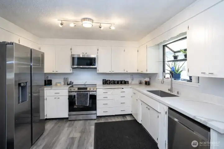 The kitchen is enhanced by solid quartz countertops and stainless steel appliances, creating a clean and modern finish.