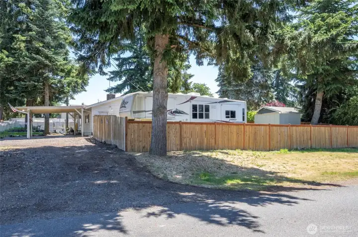 View from the corner of the property showcasing RV parking with power hookup, all within a fully fenced yard for privacy and security.