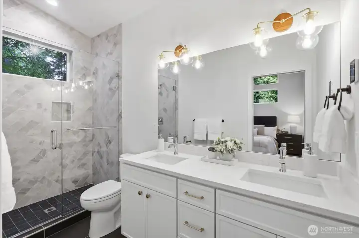 Primary suite bathroom has double vanity and extensive tilework. Primary suite bathroom has double vanity and extensive tilework.