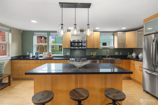 Beautiful pendant lighting, quartz countertops, and stainless appliances complement this kitchen.