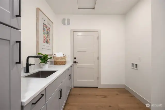 Laundry room with quartz counters and storage doubles as a mudroom. The door leads to the two car garage. Note: ceiling access to 190 sq ft of storage.