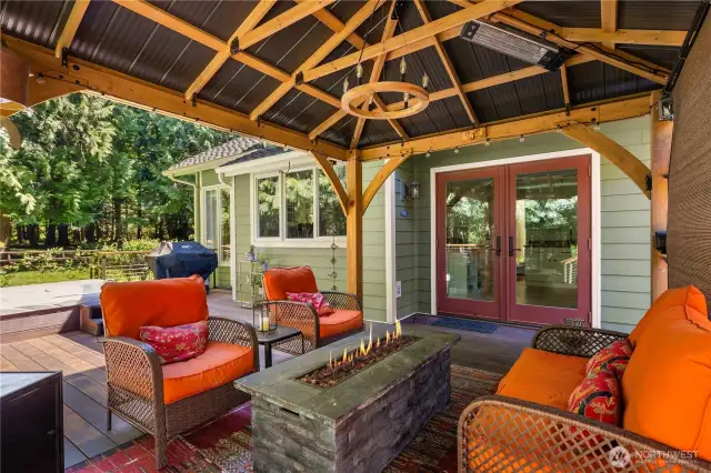 Relax and entertain year-round in this stunning covered outdoor retreat featuring a cozy fire pit, hot tub, and serene forest views.