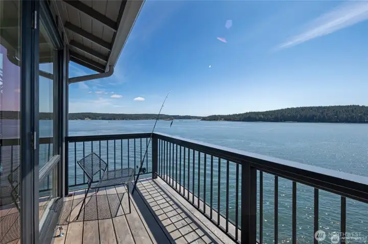 A private corner of the deck serves as the perfect fishing spot, framed by endless water views and sparkling light across Cayou Channel, highlighting the property’s rare waterfront access.