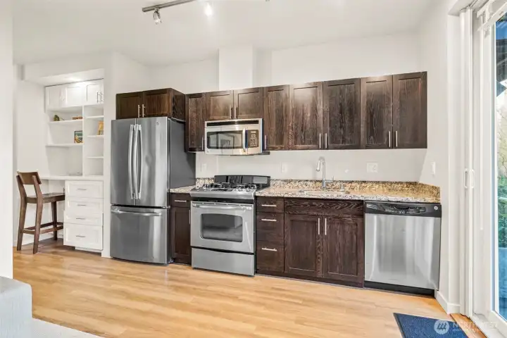 A nice open kitchen has handsome cabinetry and stainless-steel appliances.