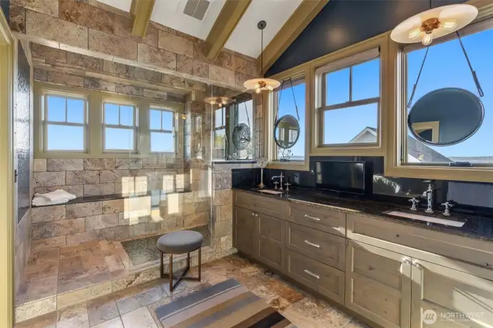The primary bathroom is beautifully finished with travertine throughout, creating a warm, spa-like atmosphere. It features dual vanities for added convenience, along with a luxurious walk-in shower that offers tranquil views, turning everyday routines into a calming, restorative experience.