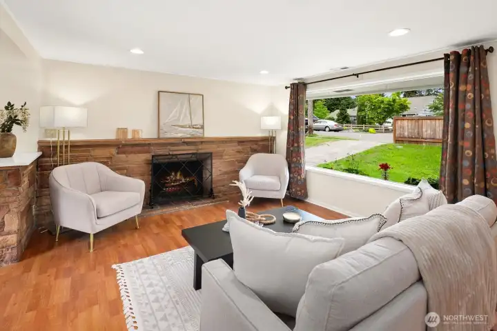Living room features wood-burning fireplace that grounds the space, with a huge picture window to let in the light.