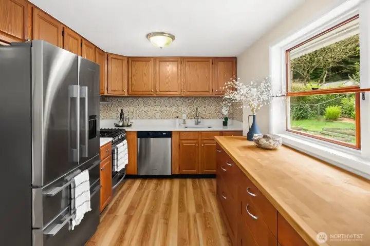 The kitchen features new quartz counter top, stainless steel appliances, a gas range, and views of the sunny back yard.  The butcher block counter top is a useful addition for storage and workspace.