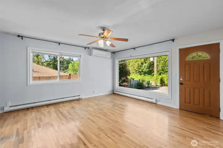 Bright and welcoming living room featuring hardwood floors, oversized picture windows and abundant natural light throughout.