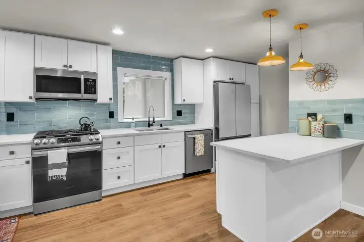 The kitchen offers stainless appliances, quartz counters and a glass tile backsplash.