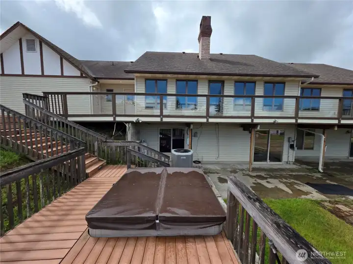 The back of the house with the deck and hot tub The back of the house with the deck and hot tub