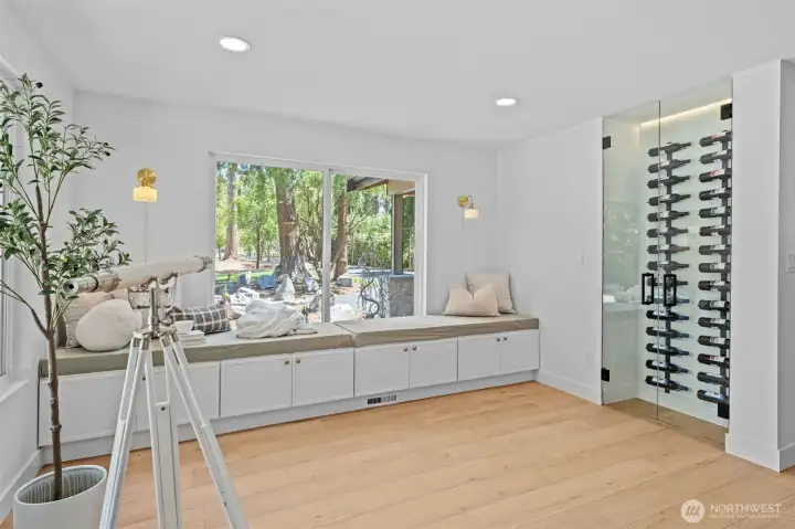 A glass-enclosed wine wall makes a striking style statement, holding a curated bottle display just steps from the built-in window seat and kitchen. A glass-enclosed wine wall makes a striking style statement, holding a curated bottle display just steps from the built-in window seat and kitchen.