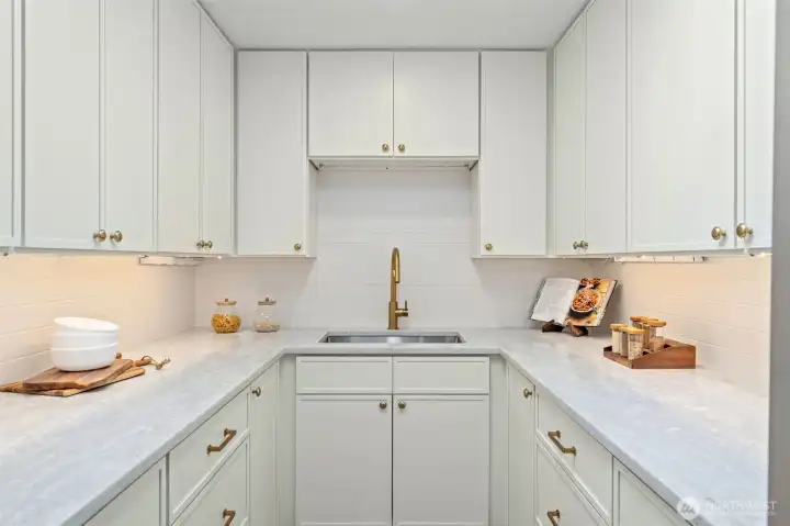 This home introduces a dedicated butler's pantry complete with its own prep sink, quartz countertops, and a full run of white shaker cabinetry with brass hardware. An additional refrigerator (not pictured) adds valuable storage and prep space, making entertaining effortless. This home introduces a dedicated butler's pantry complete with its own prep sink, quartz countertops, and a full run of white shaker cabinetry with brass hardware. An additional refrigerator (not pictured) adds valuable storage and prep space, making entertaining effortless.