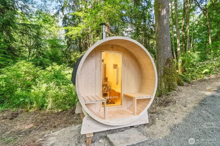 Tucked along the creek at the edge of the backyard, this cedar barrel sauna offers a private escape surrounded by towering evergreens. Built-in bench seating and a wood-burning stove create a true retreat for relaxation, right in your own backyard. Tucked along the creek at the edge of the backyard, this cedar barrel sauna offers a private escape surrounded by towering evergreens. Built-in bench seating and a wood-burning stove create a true retreat for relaxation, right in your own backyard.