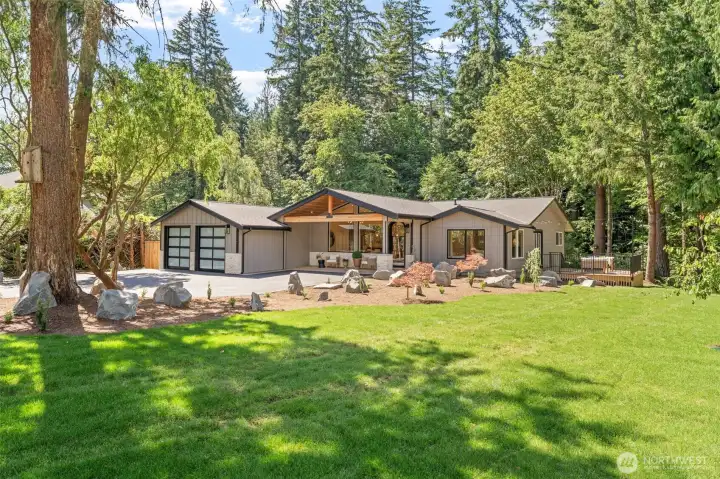 Set against a backdrop of towering evergreens, this rambler showcases striking vaulted rooflines, board-and-batten siding, and a stacked stone accent at the garage. Sculptural boulder landscaping and Japanese maples frame the entry, creating a serene, park-like setting from every angle. Set against a backdrop of towering evergreens, this rambler showcases striking vaulted rooflines, board-and-batten siding, and a stacked stone accent at the garage. Sculptural boulder landscaping and Japanese maples frame the entry, creating a serene, park-like setting from every angle.