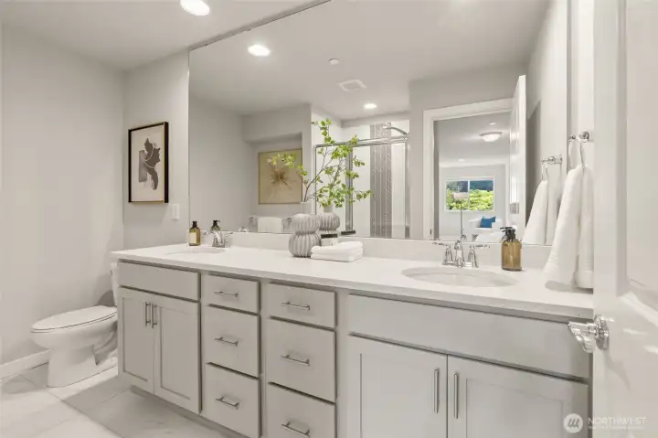 En suite bath with dual vanity, terrazzo-style quarts, and designer tile finishes.