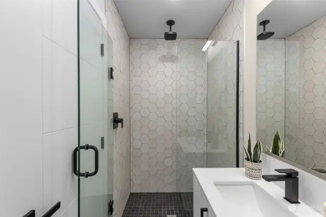 Step into this stunning walk-in shower, where every detail screams luxury. The bold hexagonal tiles, sleek black fixtures, and glass enclosure make this space feel like a private sanctuary.