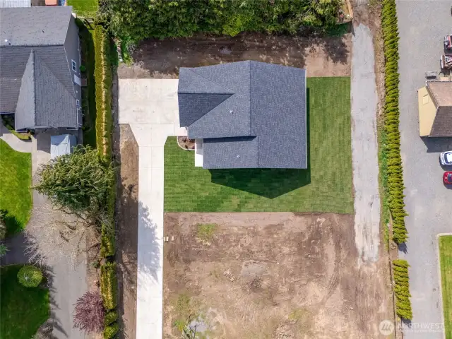 Aerial view of the home, highlighting its efficient and compact layout with a fully paved driveway leading to the front steps.