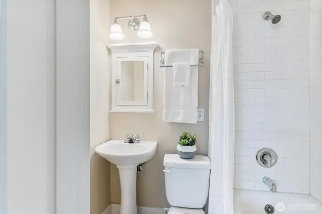 Functional bathroom with full tub, white tile walls, and modern touches that keep the historic charm intact.