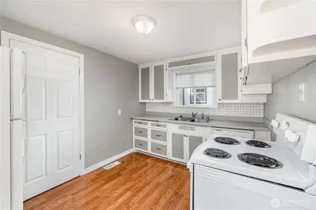 The kitchen offers light cabinetry, ample storage, generous counter space, and a charming window above the sink.
