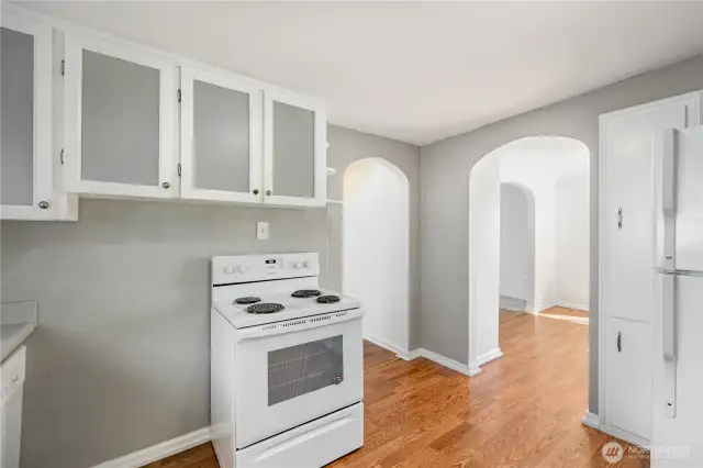 The kitchen also offers matching white appliances and continued arched doorways.