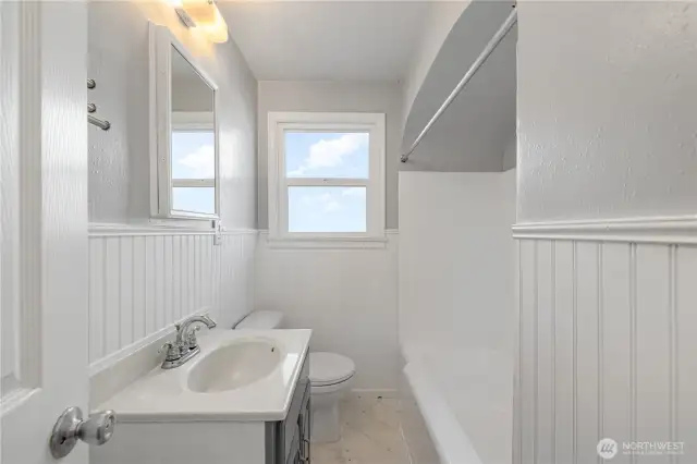 Charming full bathroom accented with wainscoting and natural light.
