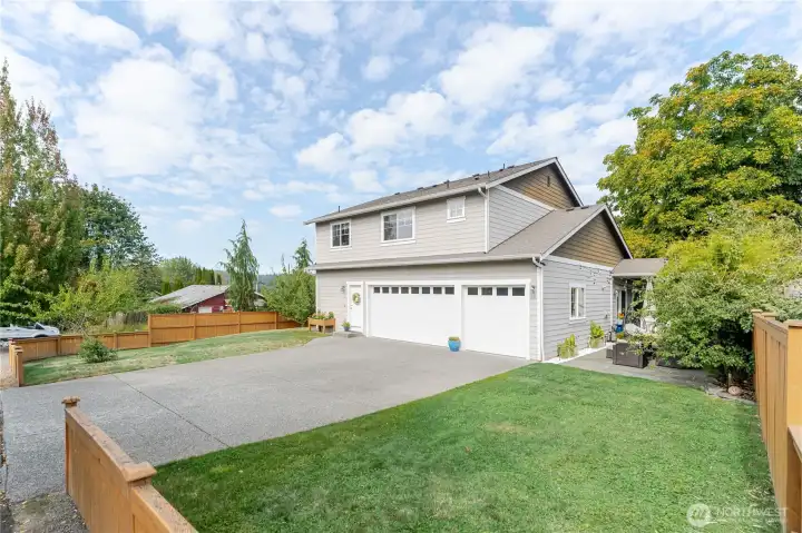 Spacious driveway and three-car garage, accessed through a back alley, offer convenience and privacy, while lush landscaping and a cozy patio create the perfect setting for outdoor gatherings or quiet morning coffee
