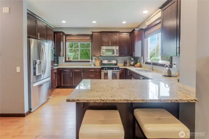 Well-equipped kitchen with rich cabinetry, granite surfaces, and stainless-steel appliances, featuring a central peninsula with casual seating for easy mornings or impromptu gatherings