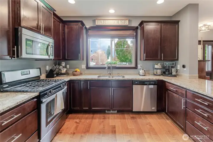 Another view of the spacious kitchen, showcasing abundant cabinetry, sleek granite counters, and stainless-steel appliances, designed for effortless cooking and organized living