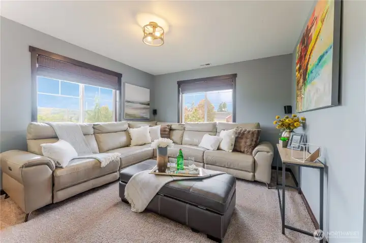 As you arrive upstairs, the bonus room welcomes you as a cozy TV lounge—perfect for movie nights, game days, or relaxed downtime with family and friends