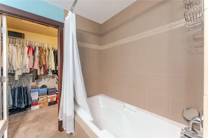 View from the primary bath into the expansive walk-in closet—offering generous storage, thoughtful organization, and direct access to a spacious attic for even more versatility