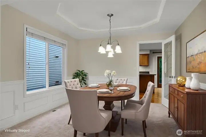 Virtually staged spacious dining room with tray ceiling and a beautiful glass door entry to the kitchen.