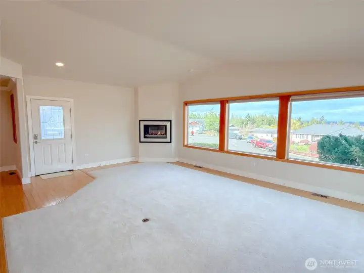 Living room portion of great room with three large windows bringing in the natural light and views.