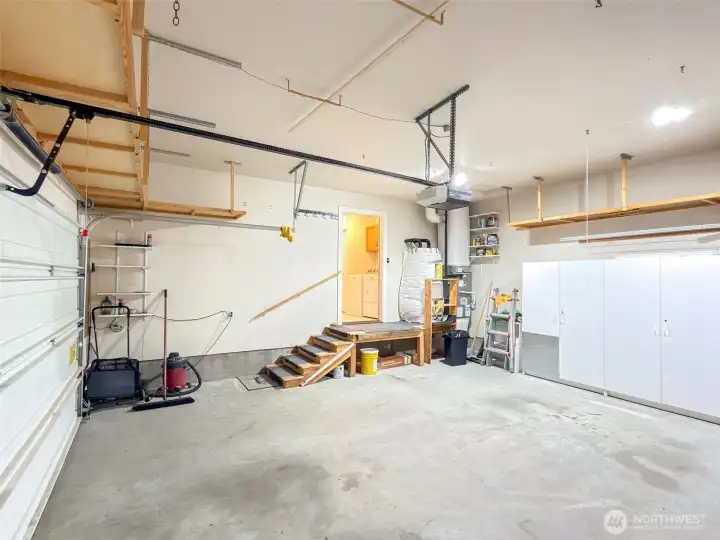 Opposite side view of the attached garage, showing additional storage shelving and entry to the laundry room.