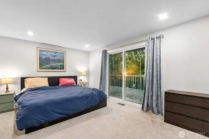 The expansive primary suite accommodates a king bed with ease and boasts a spa-inspired tile bath, a spacious walk-in closet, and direct access to the upper deck overlooking tranquil trees.