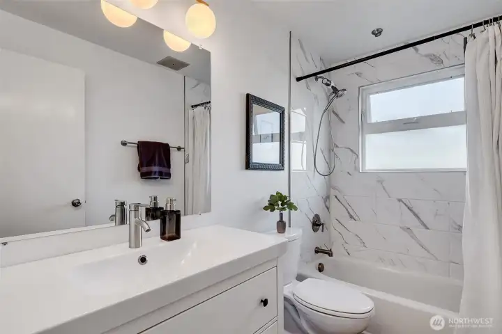 Updated bathroom with newer sink, vanity and tile.
