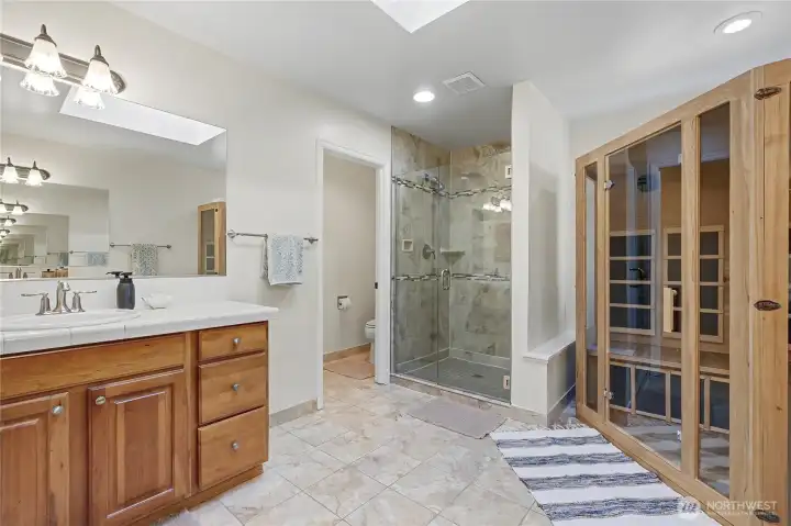 Primary ensuite bath view from hallway/closets. Included sauna on your right, amazing shower and private water closet. Solid surface counter tops and gorgeous cabinetry, of course!