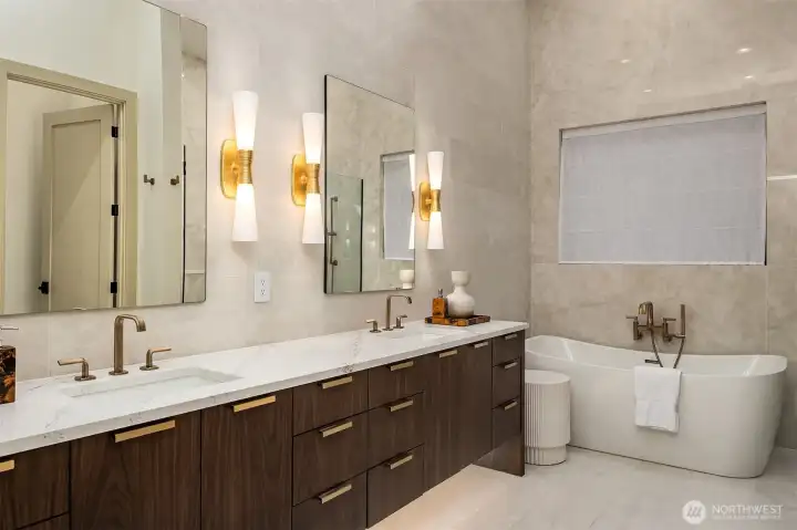 Dual stained walnut vanities with Brizo Allaria Luxe Gold fixtures, floor-to-ceiling Opalite slabs, and a freestanding MAAX soaking tub — the kind of morning routine that doesn't feel like a routine at all.